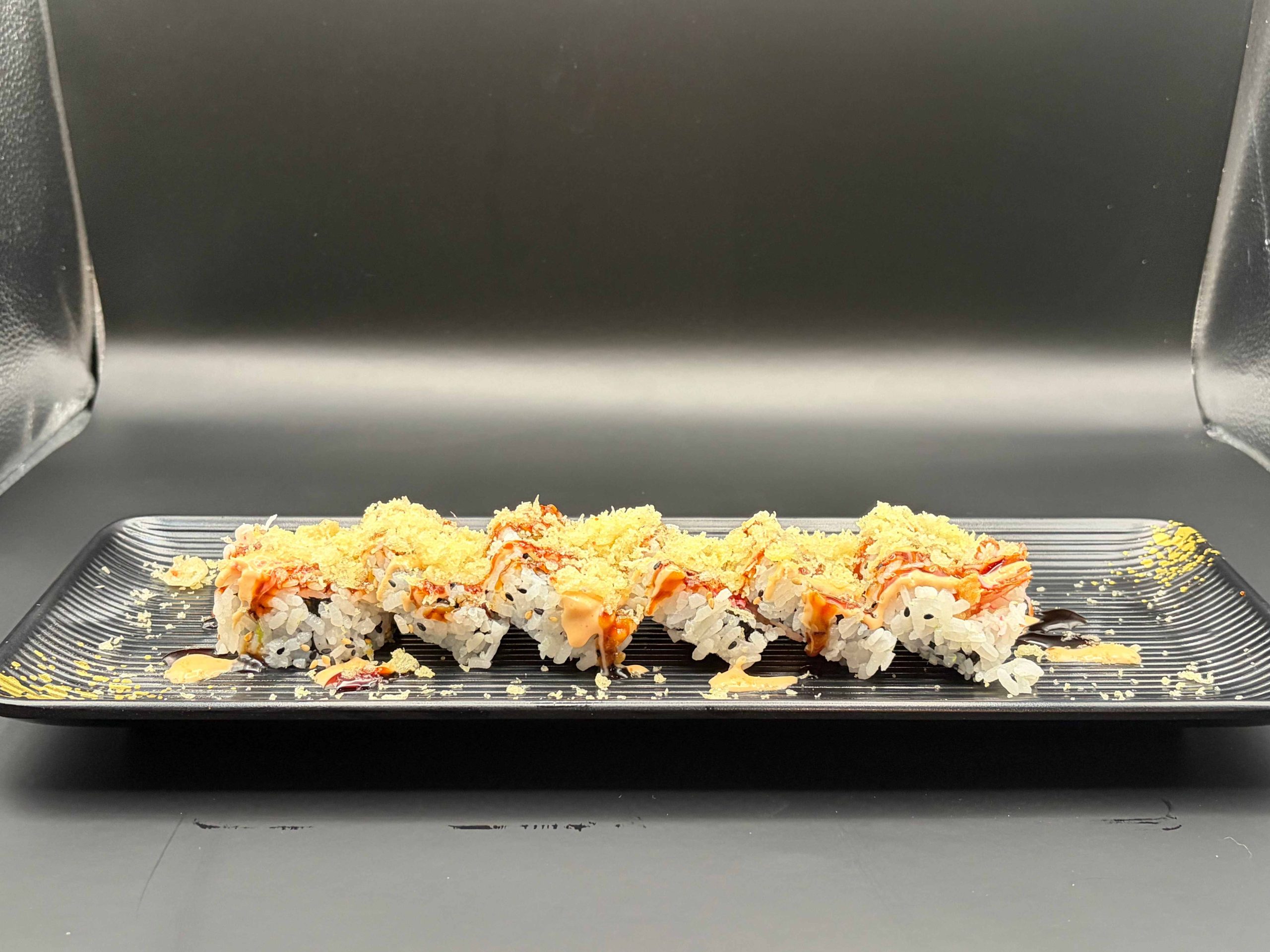Crunchy sushi roll topped with spicy crab mix, crispy flakes, and drizzled sauces