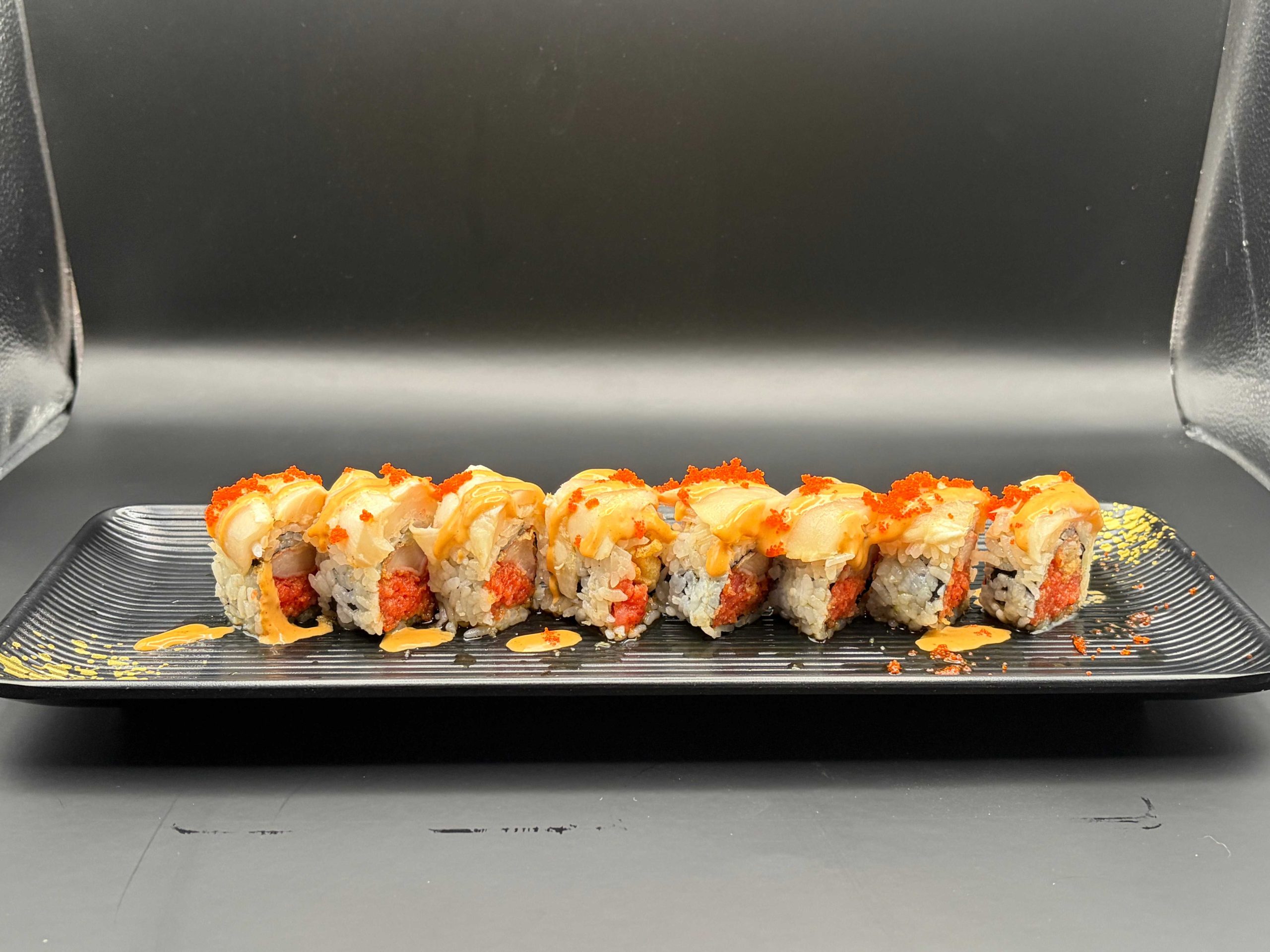 Specialty sushi roll topped with creamy seafood, spicy mayo, and orange fish roe