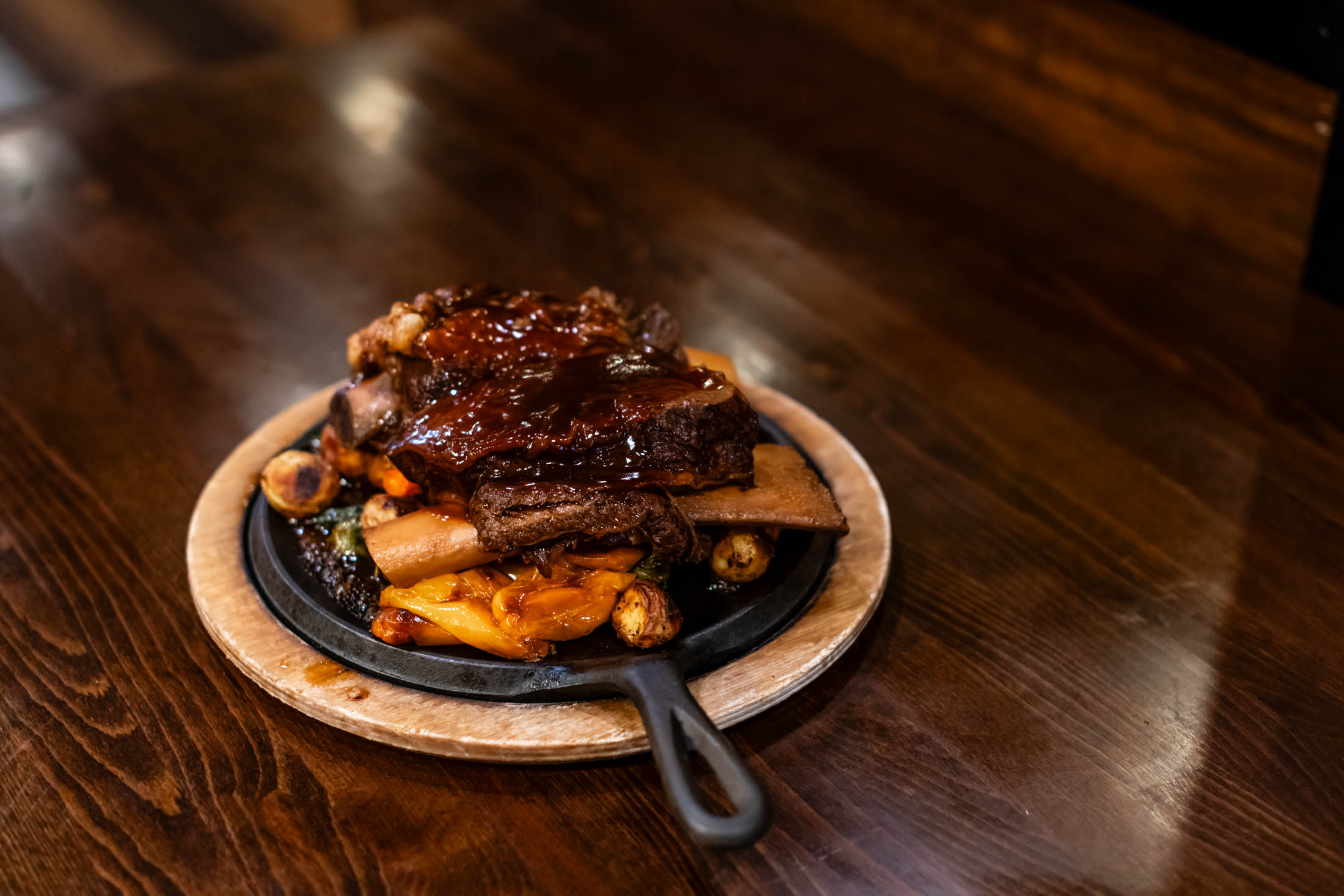 Braised glazed beef short ribs on sizzling iron skillet with roasted veggies at Canaan Chinese Cuisine, a Chinese Restaurant in CA