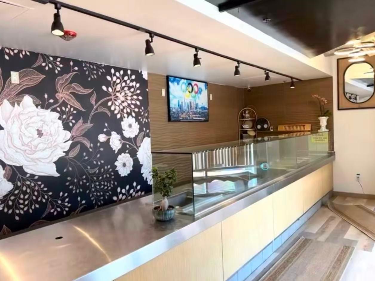 Elegant restaurant interior with floral wall and display counter at EatGrand, a Japanese Restaurant in Los Angeles