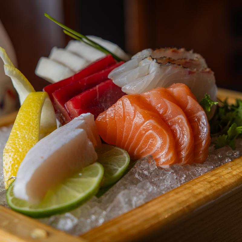 A wood-grain-patterned plate holds an abundance of sashimi.