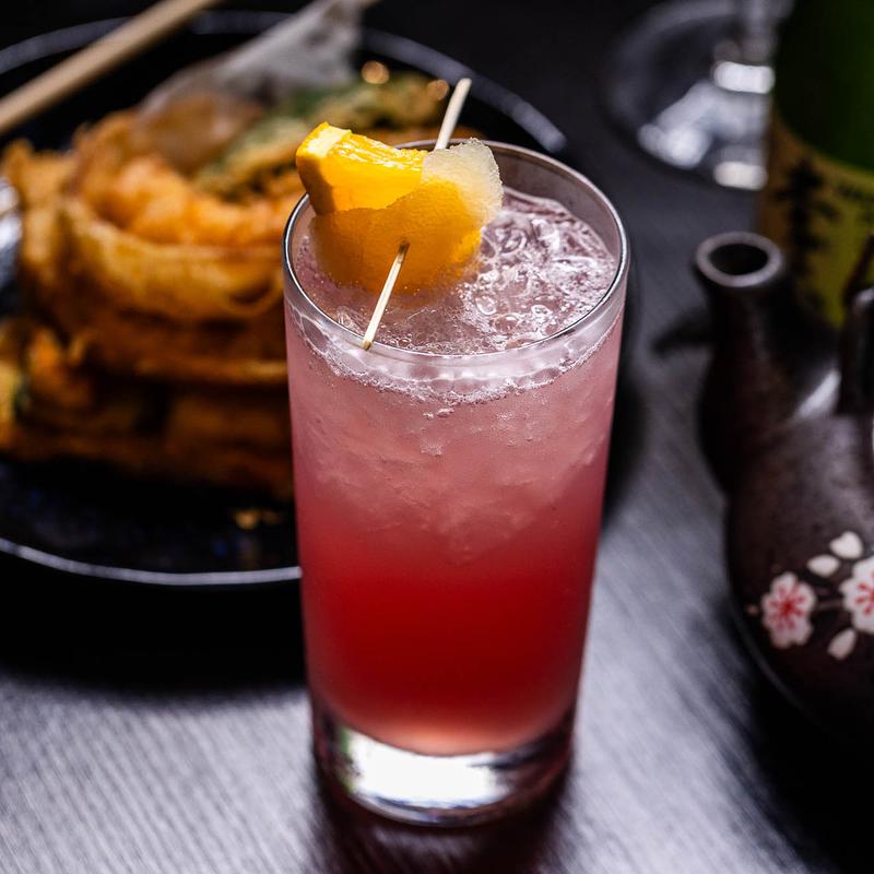 A glass of red drink topped with a slice of orange.