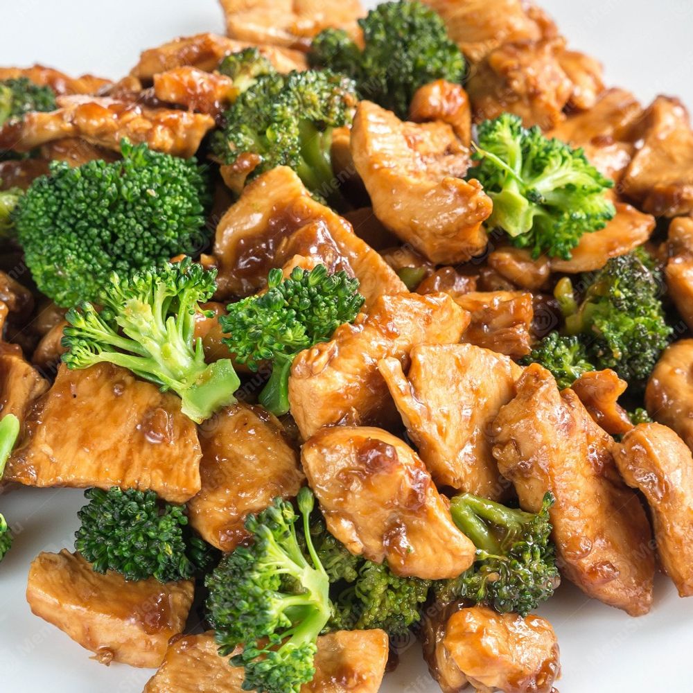 Chicken pieces and broccoli in brown sauce on a white plate