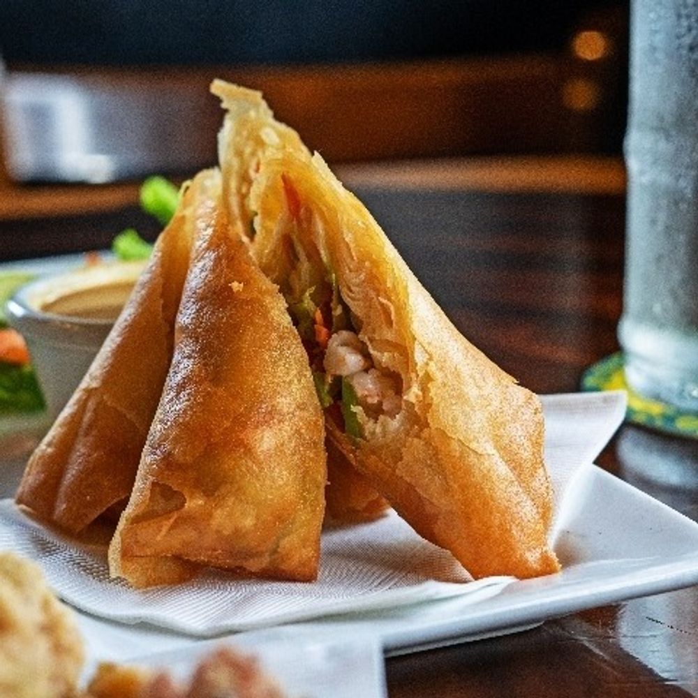Crispy fried spring rolls on a white plate with dipping sauce