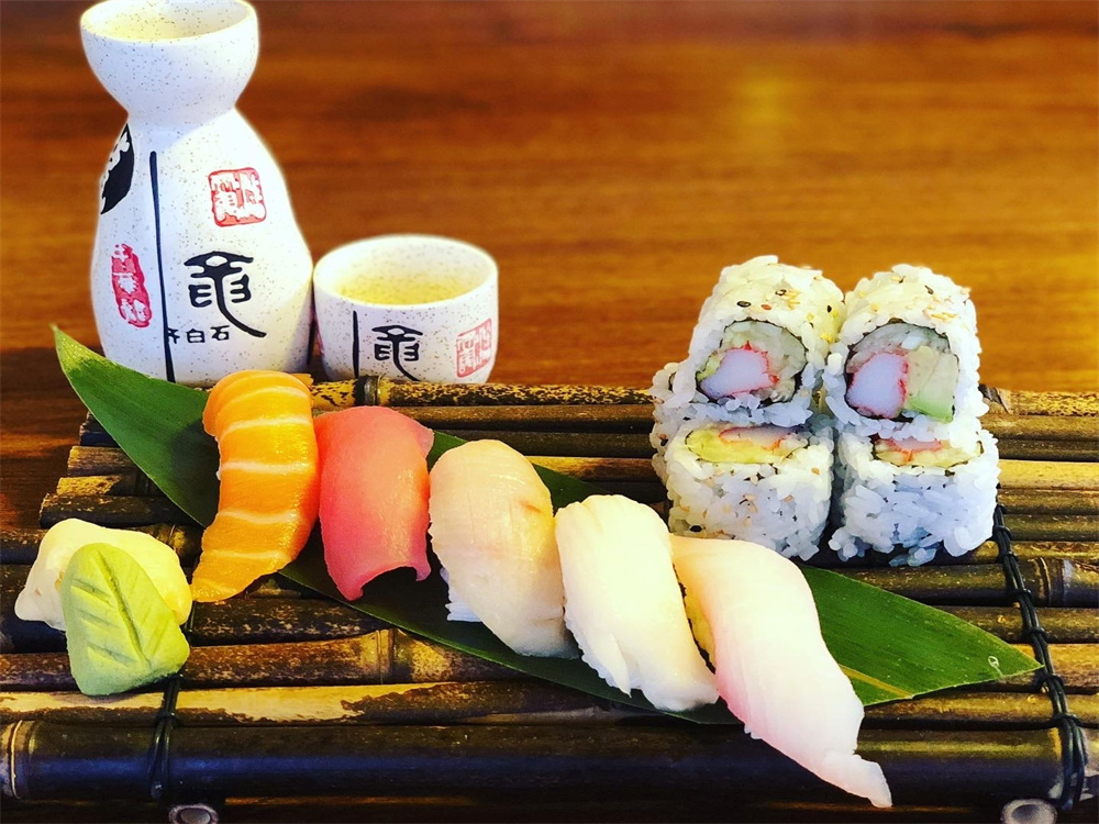 Assorted nigiri sushi and crab maki set paired with sake bottle and cup at Edo Japan, a Japanese Restaurant in Texas City