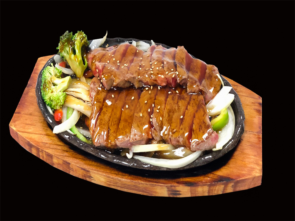 Sizzling teriyaki steak slices on hot stone plate with broccoli and onions at Edo Japan, a Japanese Restaurant in Texas City