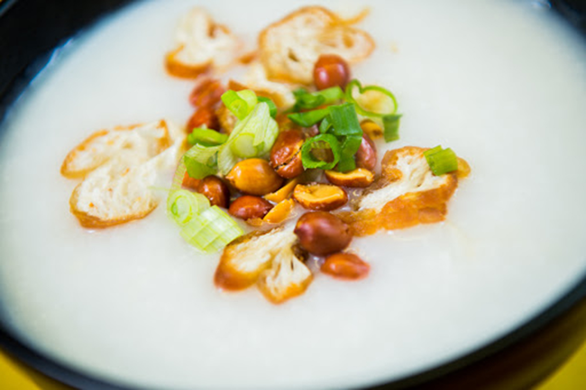 Smooth plain congee topped with fried dough bits, peanuts and chopped green onions at E Noodle Chinatown, a Chinese Restaurant in New York