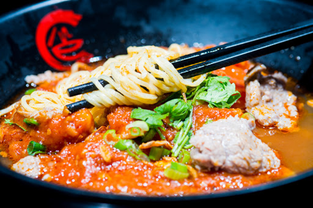Tomato beef noodle soup with fresh cilantro and green onion toppings at E Noodle Chinatown, a Chinese Restaurant in New York