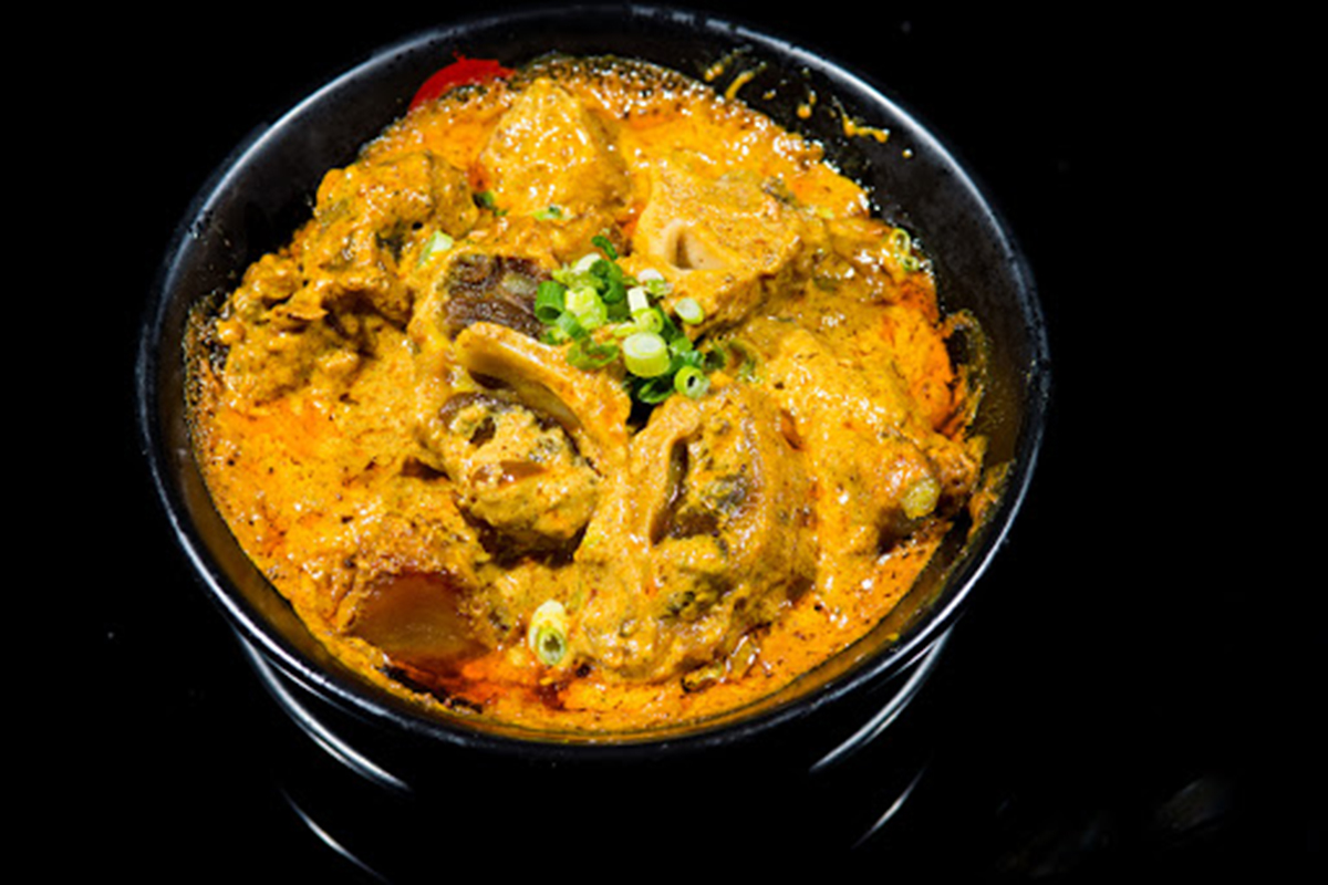 Creamy yellow curry beef bone stew garnished with chopped green onions at E Noodle Chinatown, a Chinese Restaurant in New York