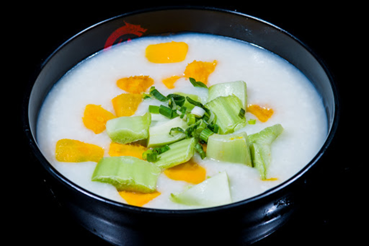 Plain congee mixed with pumpkin chunks and chopped green celery stalks at E Noodle Chinatown, a Chinese Restaurant in New York