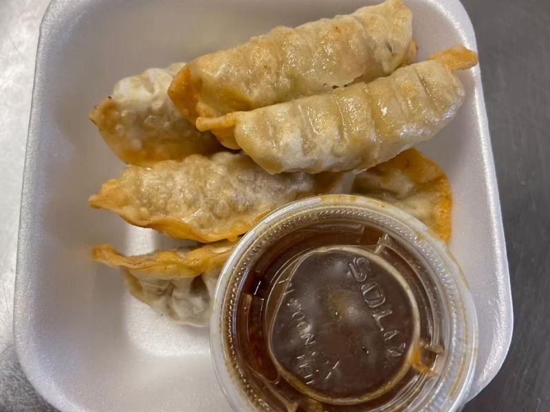 EZ-YUMMY-FOOD-Asian-Restaurant-Pork-gyoza-Ahoskie Delicious pork gyoza with a side of dipping sauce, in a foam tray at EZ YUMMY FOOD, a Asian Restaurant in Ahoskie