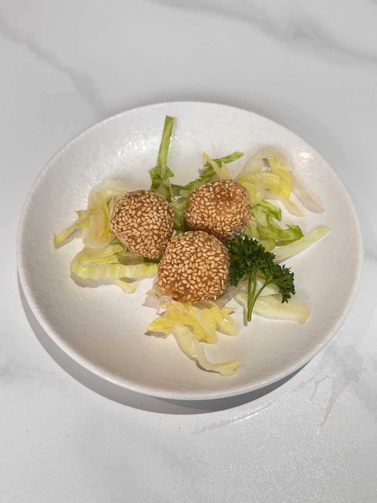 Three fried sesame balls served with lettuce garnish at Takumi, a Japanese Restaurant in Fairview Heights