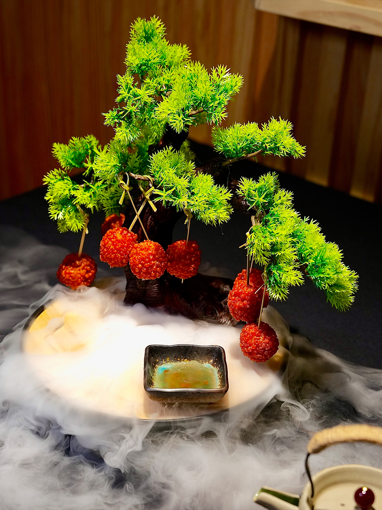 Floral-Chinese-Restaurant-New-York Dessert of red, textured spheres (possibly candied haw or bayberries) hanging from a small artificial pine tree, served on dry ice mist.