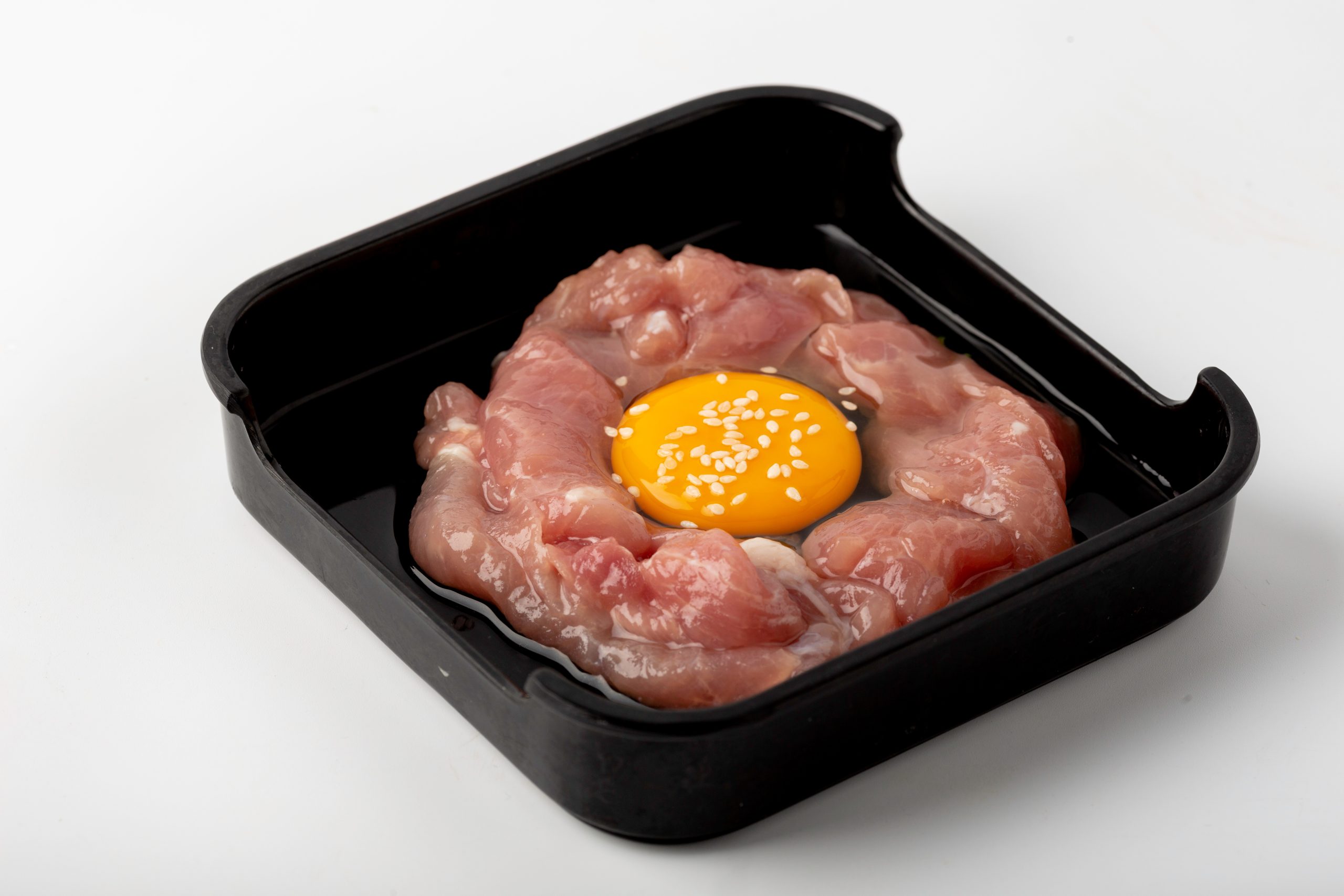 Raw sliced pork topped with a fresh egg yolk and sesame at Firestone Hotpot & BBQ Restaurant in Tallahassee