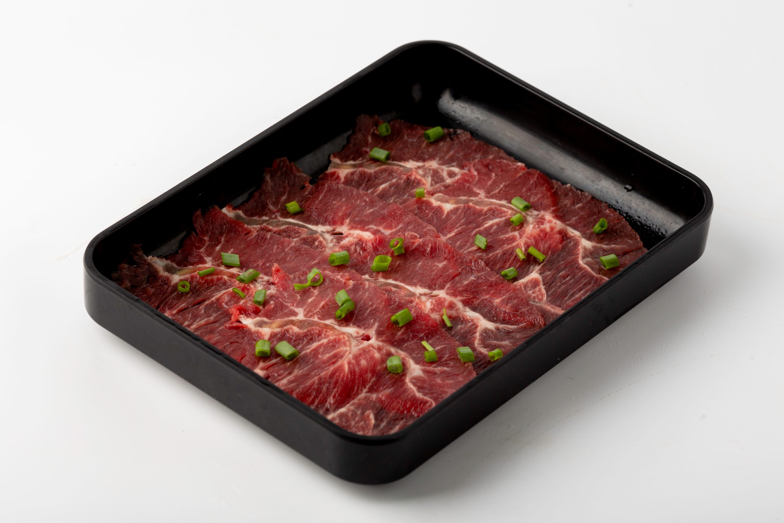 Raw marbled beef slices topped with green onions at Firestone Hotpot & BBQ Restaurant in Tallahassee