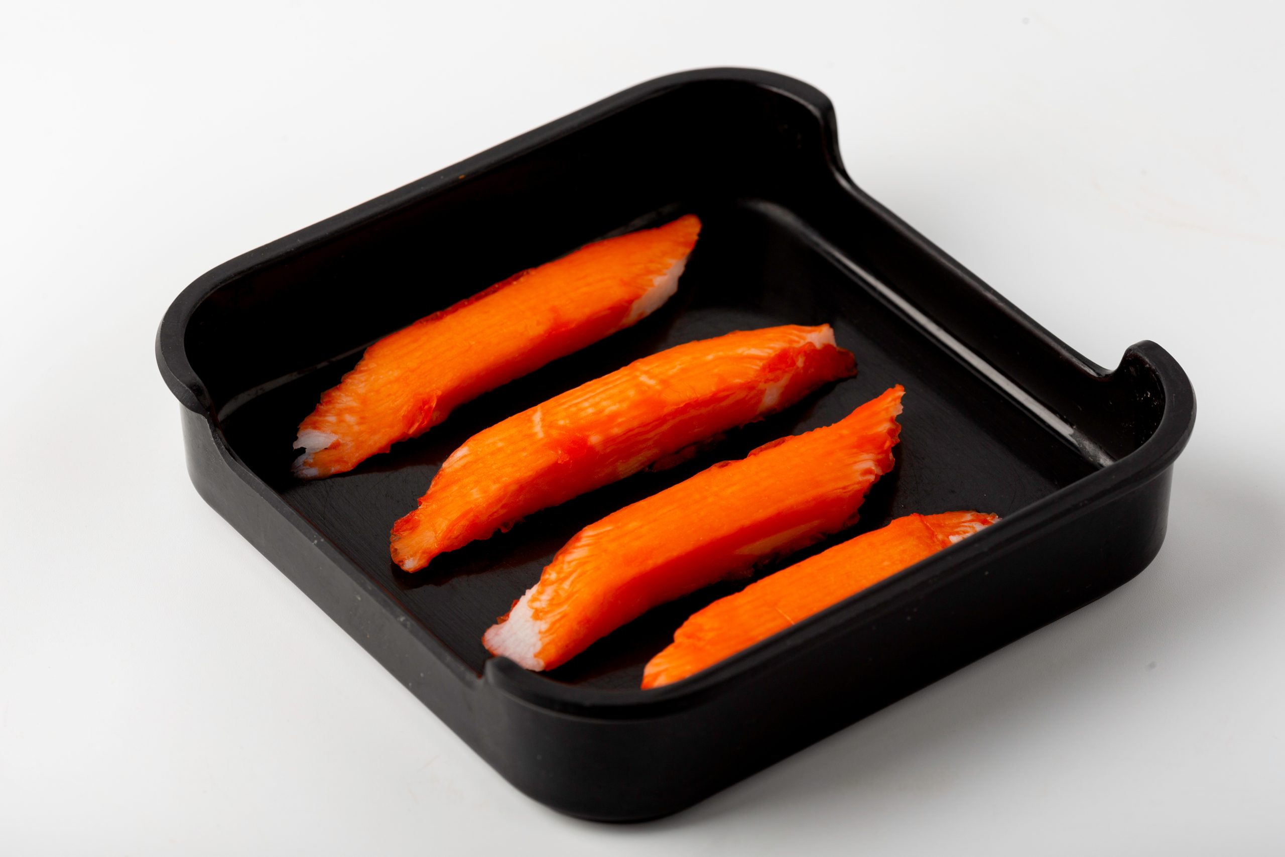 Four imitation crab sticks in a black tray at Firestone Hotpot & BBQ Restaurant in Tallahassee