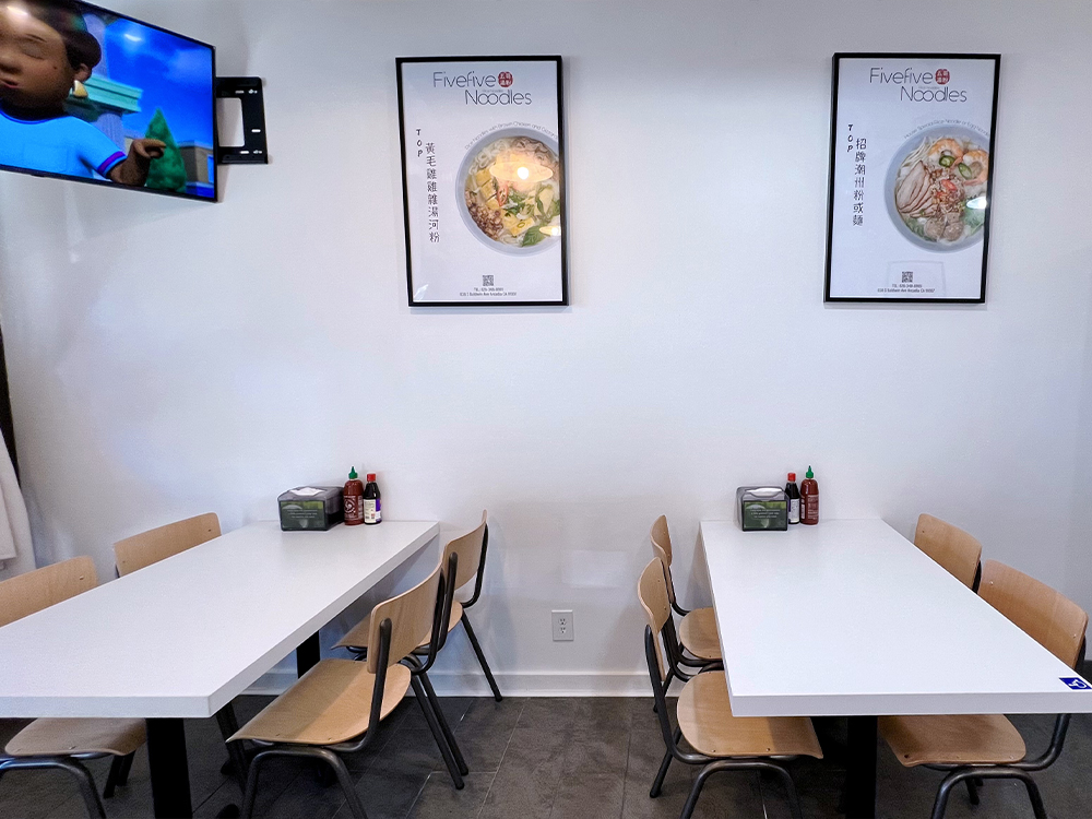 Fivefive Noodles dining area with two tables, chairs, and menu posters