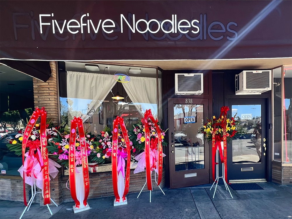Fivefive Noodles restaurant storefront with open sign and grand opening flowers