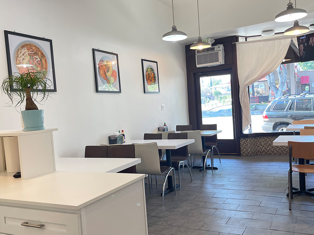 Fivefive Noodles dining space near entrance with tables, chairs, and wall decor