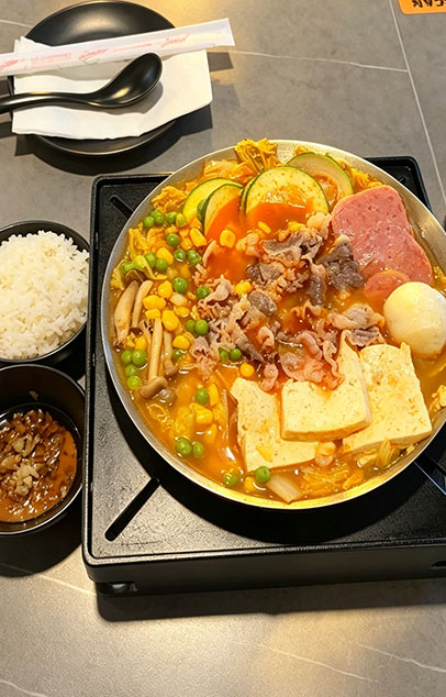 Beef hot pot with tofu, zucchini, corn, peas, mushrooms, and rice, served with dipping sauce