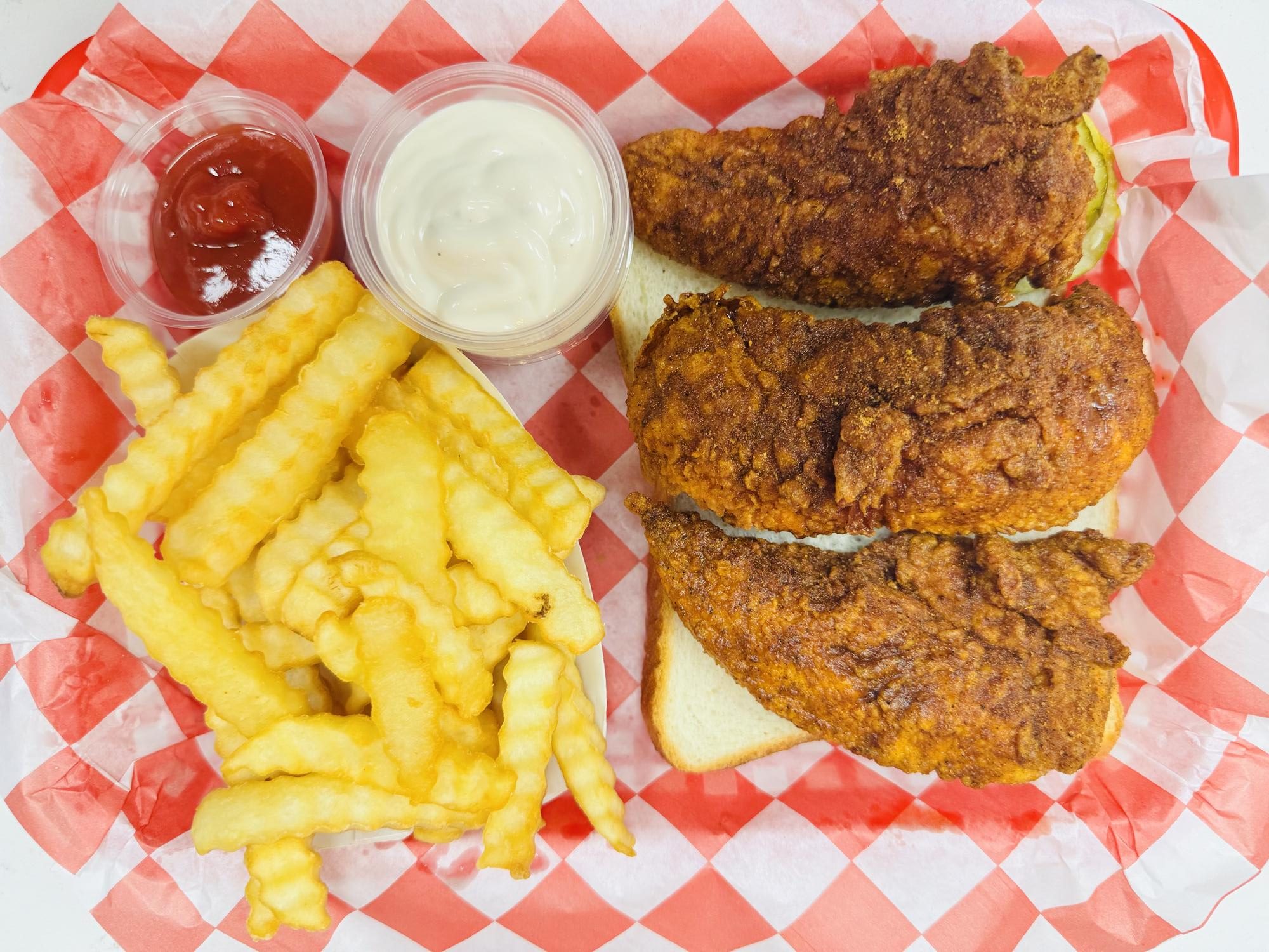 Fried chicken sandwich with fries and sauces at Frank’s Hot Chicken, a Fast - Food Restaurant in Jonesboro