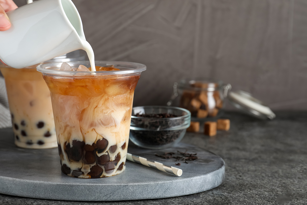 Pouring milk into iced boba tea with tapioca pearls at Fruitbite Smoothie, a Smoothie & Fruit Tea Shop in Broomfield