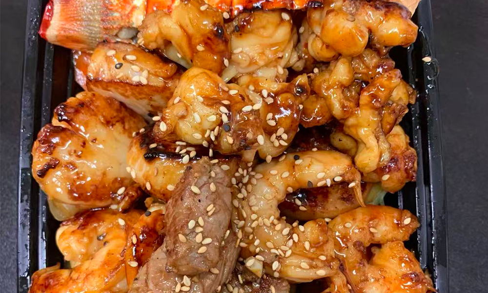 Platter of teriyaki seafood and beef with sesame seeds. Aburi Salmon Sushi Roll at Fuji Hibachi&Sushi in Monroe