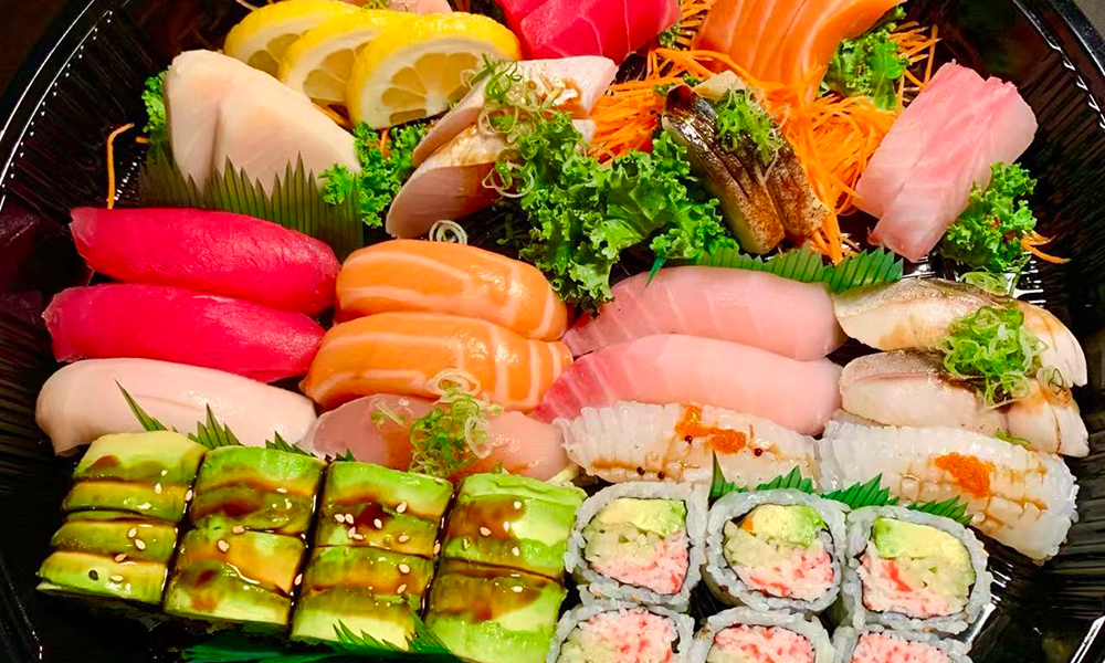 Platter of diverse sushi and sashimi with lemon and veggies. Aburi Salmon Sushi Roll at Fuji Hibachi&Sushi in Monroe