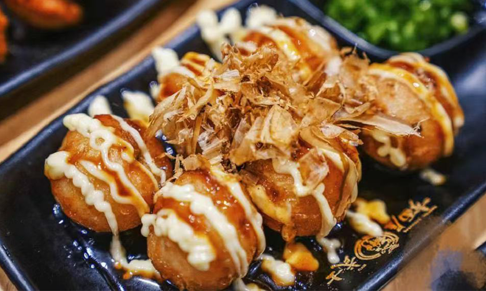 Savory octopus balls topped with mayo and bonito flakes at Fuji Ramen Japanese Cuisine, a Japanese Restaurant in New Philadelphia