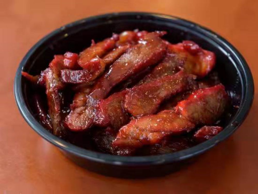 Glazed red barbecue pork slices in takeout bowl
