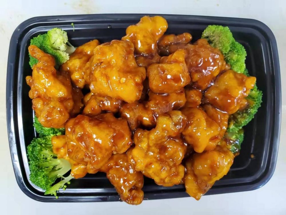 Orange chicken with broccoli in rectangular takeout container