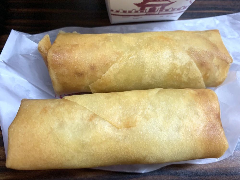 Two crispy fried spring rolls on paper