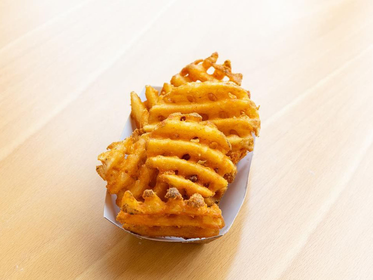 Crispy golden waffle fries in a paper tray at Fusion Poke, an Asian Fusion Restaurant in Milwaukee
