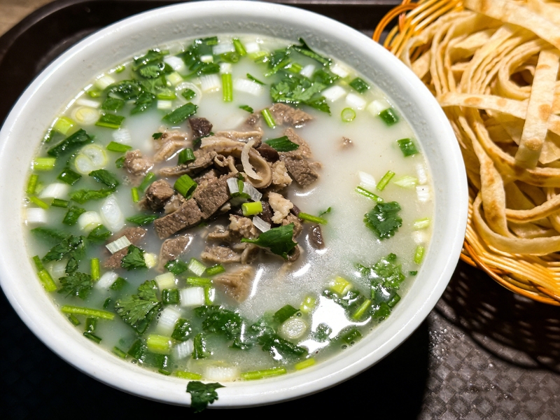 Creamy offal soup with cilantro, scallions and fried bread sticks at Gao Qunsheng's Spicy Soup, a Chinese Restaurant in Flushing