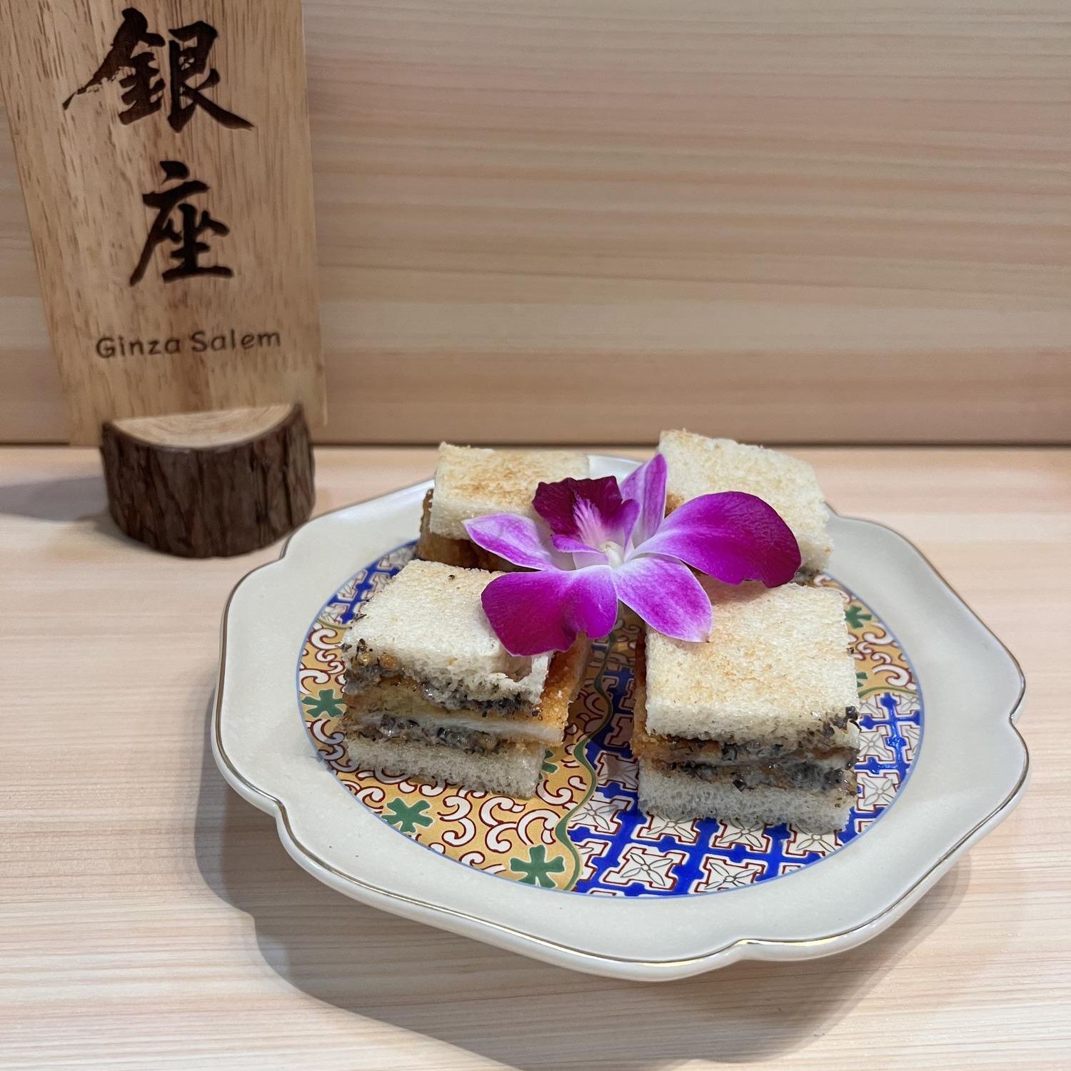 Small sandwiches with layered fillings, garnished with orchid at Ginza Sushi and Ramen, a Japanese Restaurant in Salem