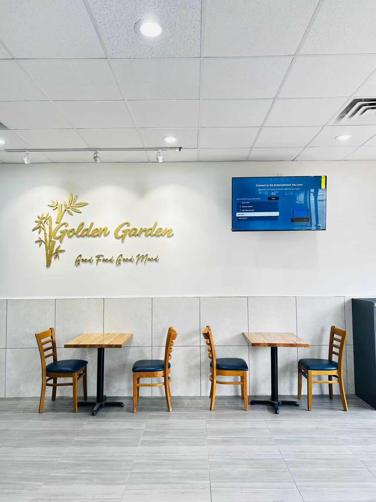 Spacious clean dining room with two wooden table sets and branded bamboo wall decor at Golden Garden, a Chinese Restaurant in Pompton Lakes