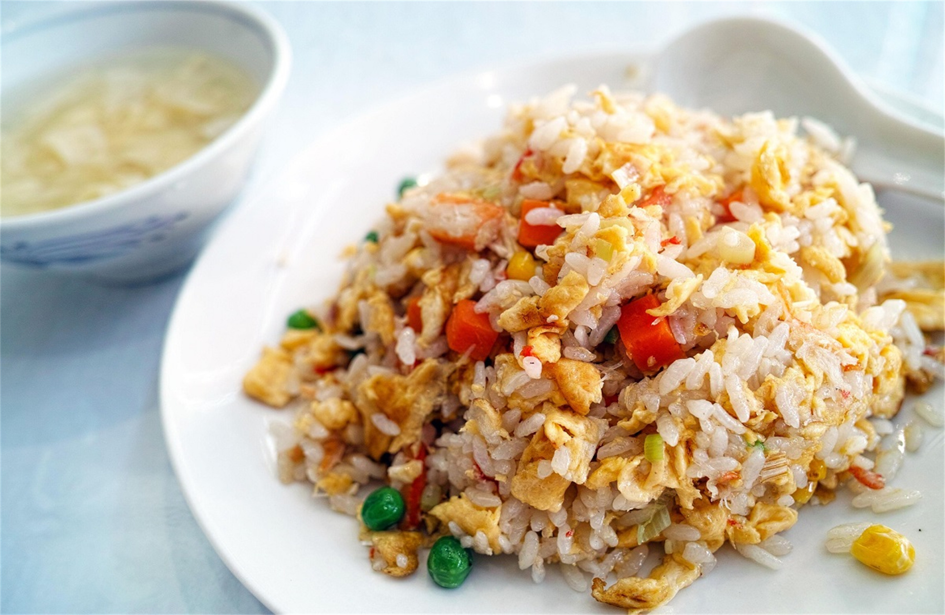 An appetizing plate of egg - fried rice. The grains of rice are distinct, mixed with golden scrambled eggs, tender peas, and sweet carrot dices at Good Eats，a Chinese Restaurant in Fresno