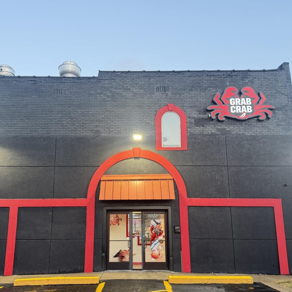 Black brick building with red accents and "Grab Crab" sign in daylight at Grab Crab, a Seafood Restaurant in Pontiac