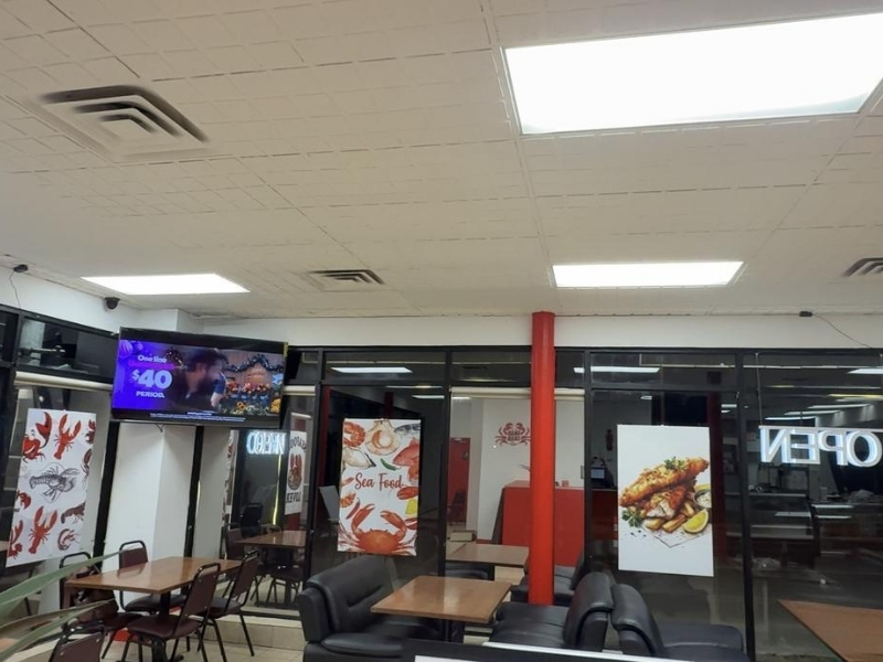 Dining space with TV and food signs at Grab Crab, a Seafood Restaurant in Pontiac
