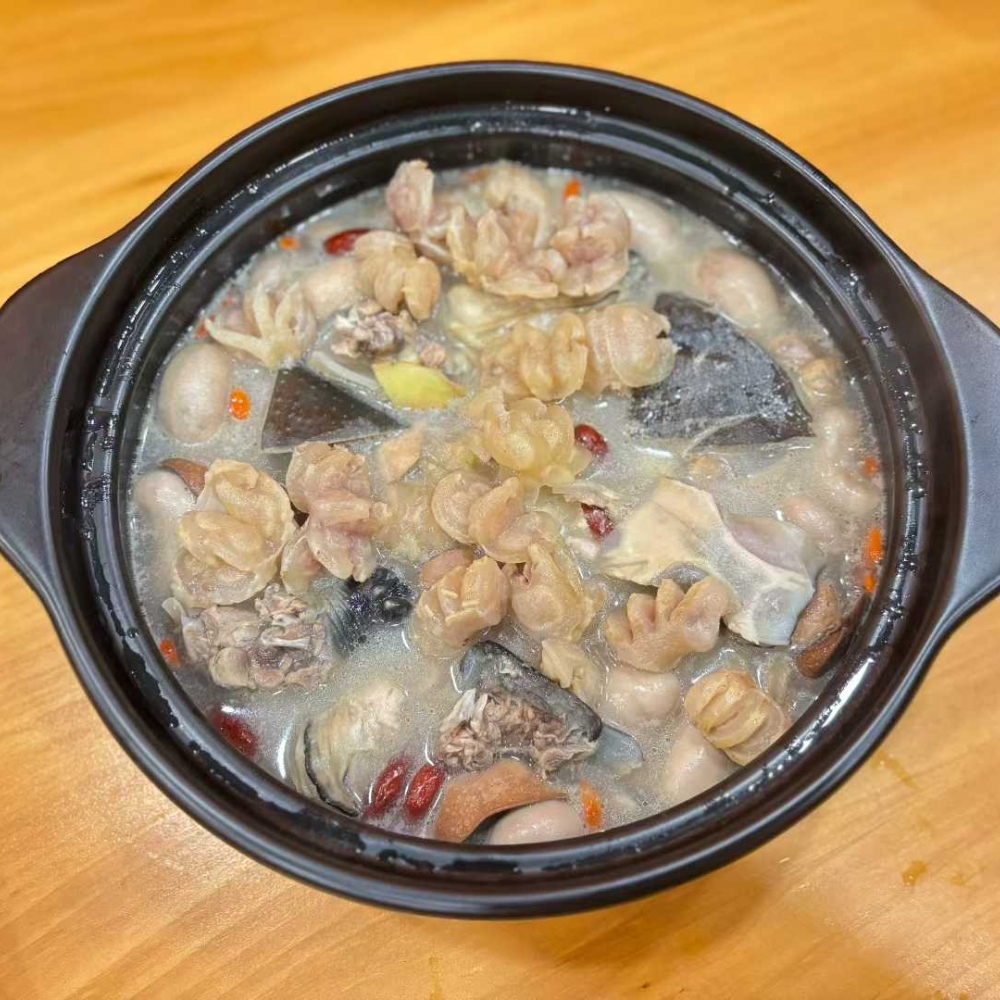 A pot of turtle soup with various ingredients at GWONGFU BEEF MIX INC, a Chinese Restaurant in Brooklyn