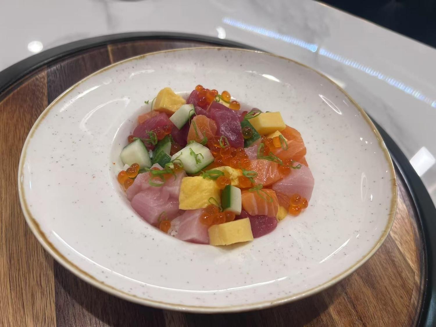 Bowl of diced sashimi with cucumber, mango, and fish roe, creating a colorful and fresh mix.