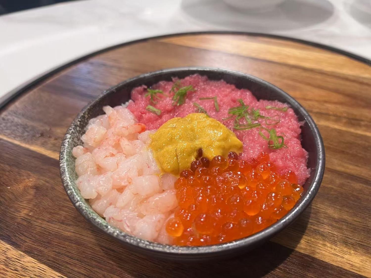 Bowl of rice with fresh shrimp, minced tuna, fish roe, and a dollop of yellow sauce.