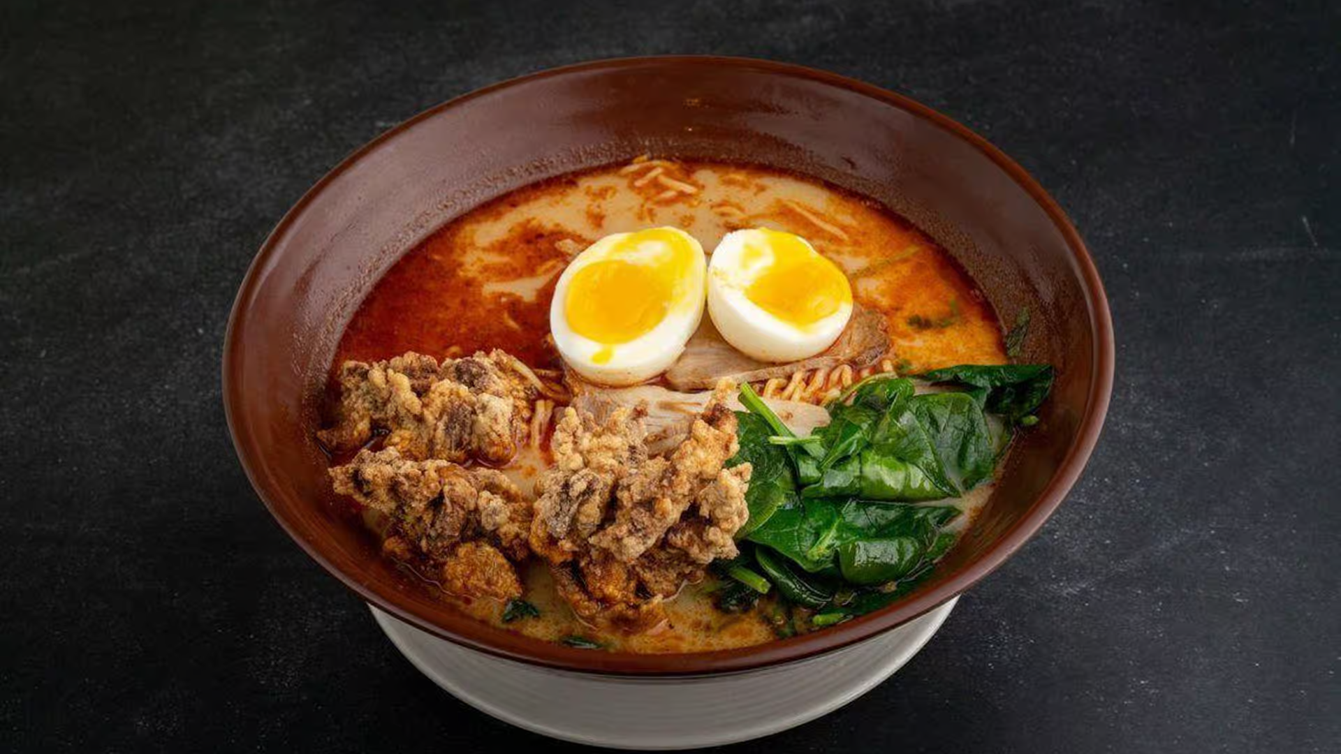 picy tonkotsu ramen with eggs, fried meat, and spinach