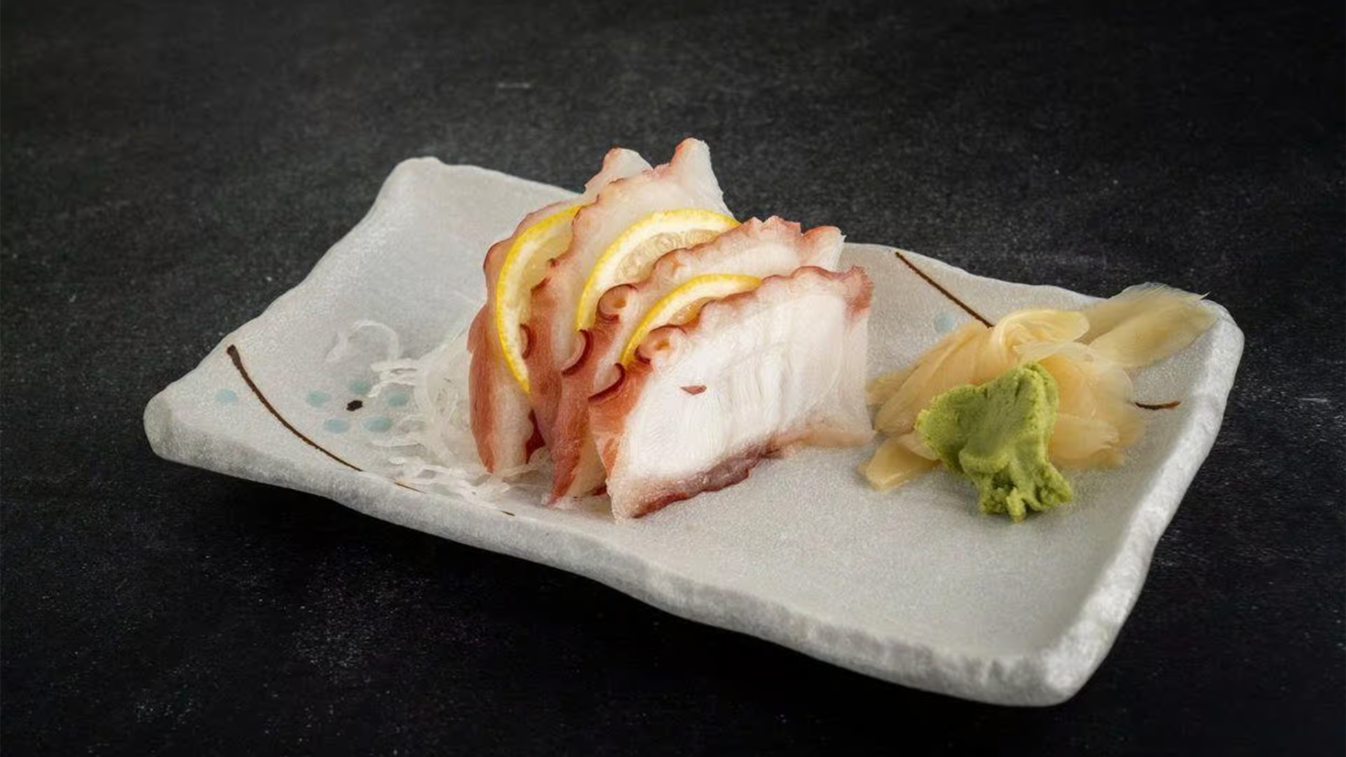 Fresh octopus sashimi with lemon, ginger, and wasabi