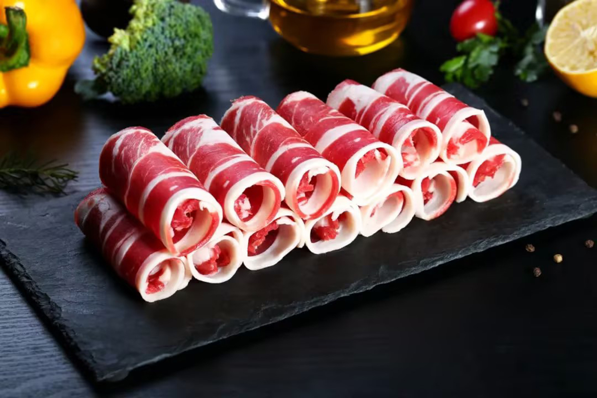 Rolls of marbled beef slices on a black slate tray at Happy Lamb Hot Pot Restaurant in Austin