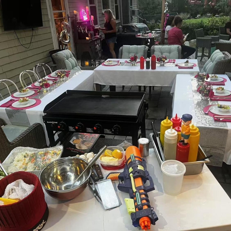 Outdoor prep area with grill, condiments, and a water gun on the table.