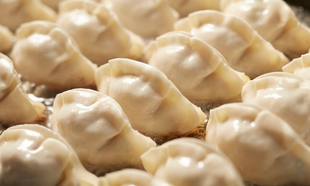 Pan-fried dumplings with golden, crispy bottoms cooking in oil at High Five Asian Street Food, a Asian restaurant in Ormond Beach