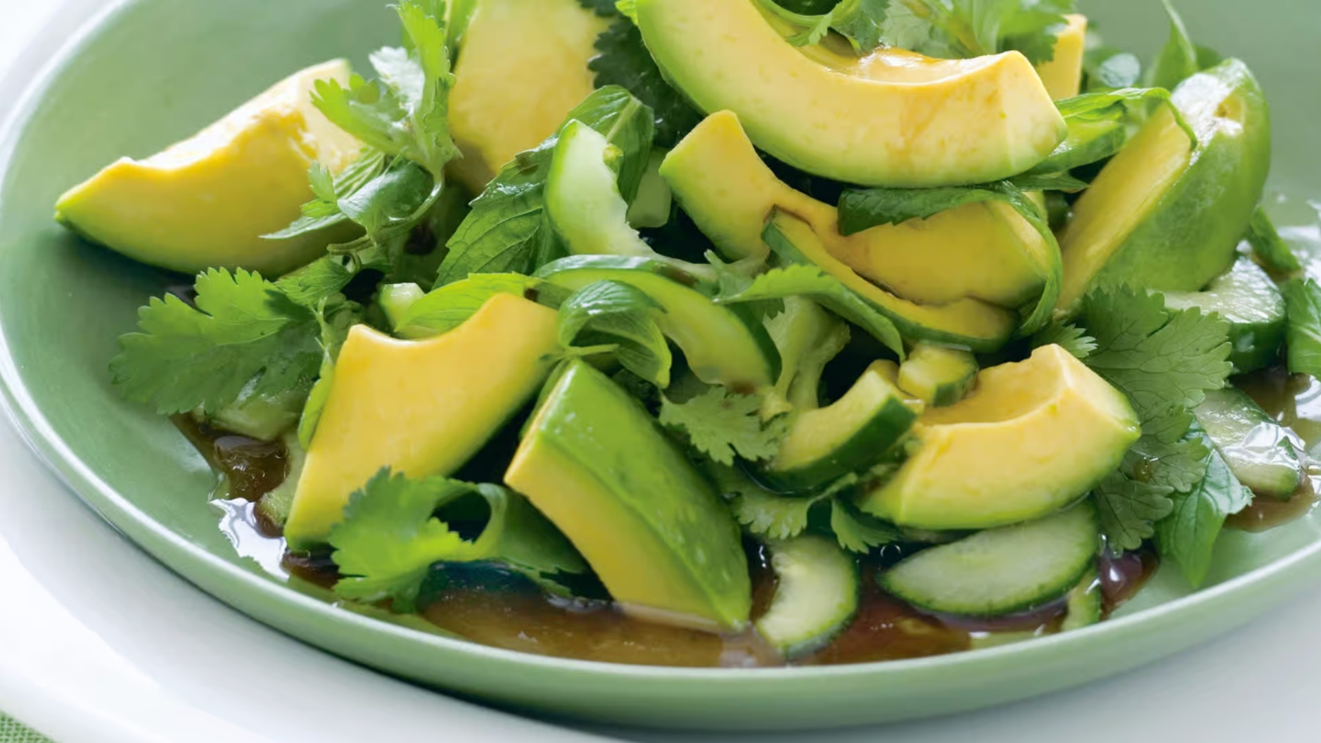 Avocado salad with cucumber and cilantro in a green bowl
