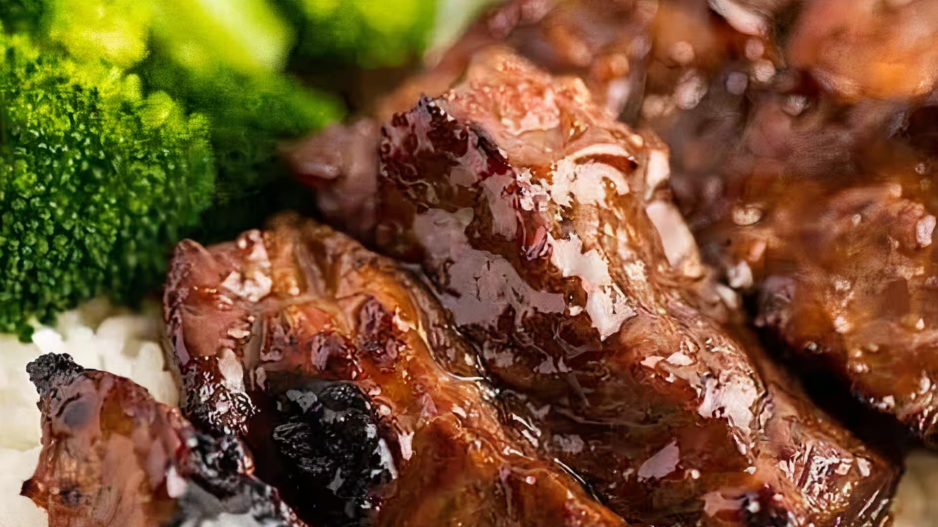 Close-up of glazed meat with rice and broccoli