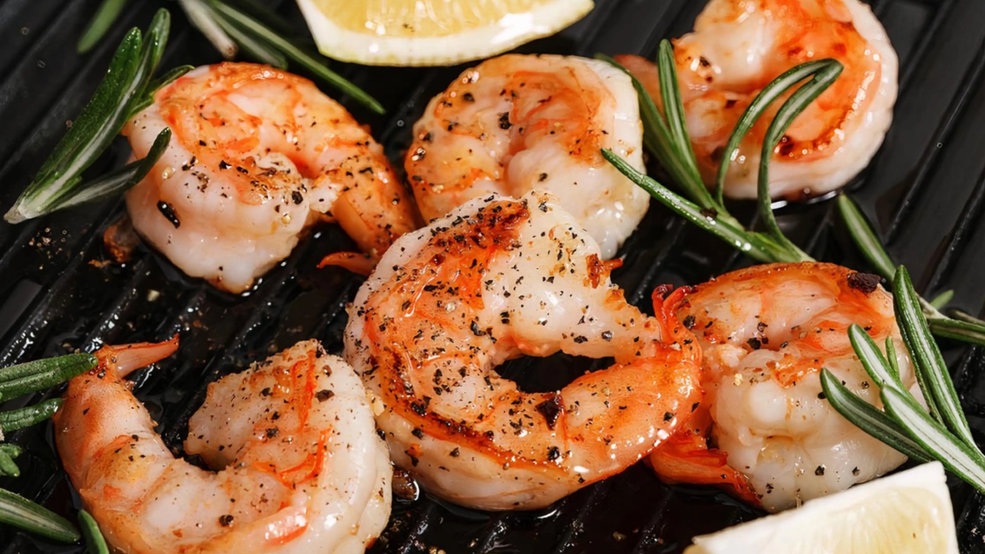 Grilled shrimp with rosemary and lemon on a black grill pan